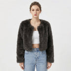 Front view of a model wearing a dark grey cropped faux fur jacket.