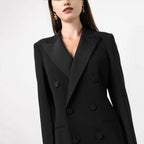 Close-up studio shot of the bodice of a black double-breasted tuxedo maxi dress, showing the satin lapels and buttons.