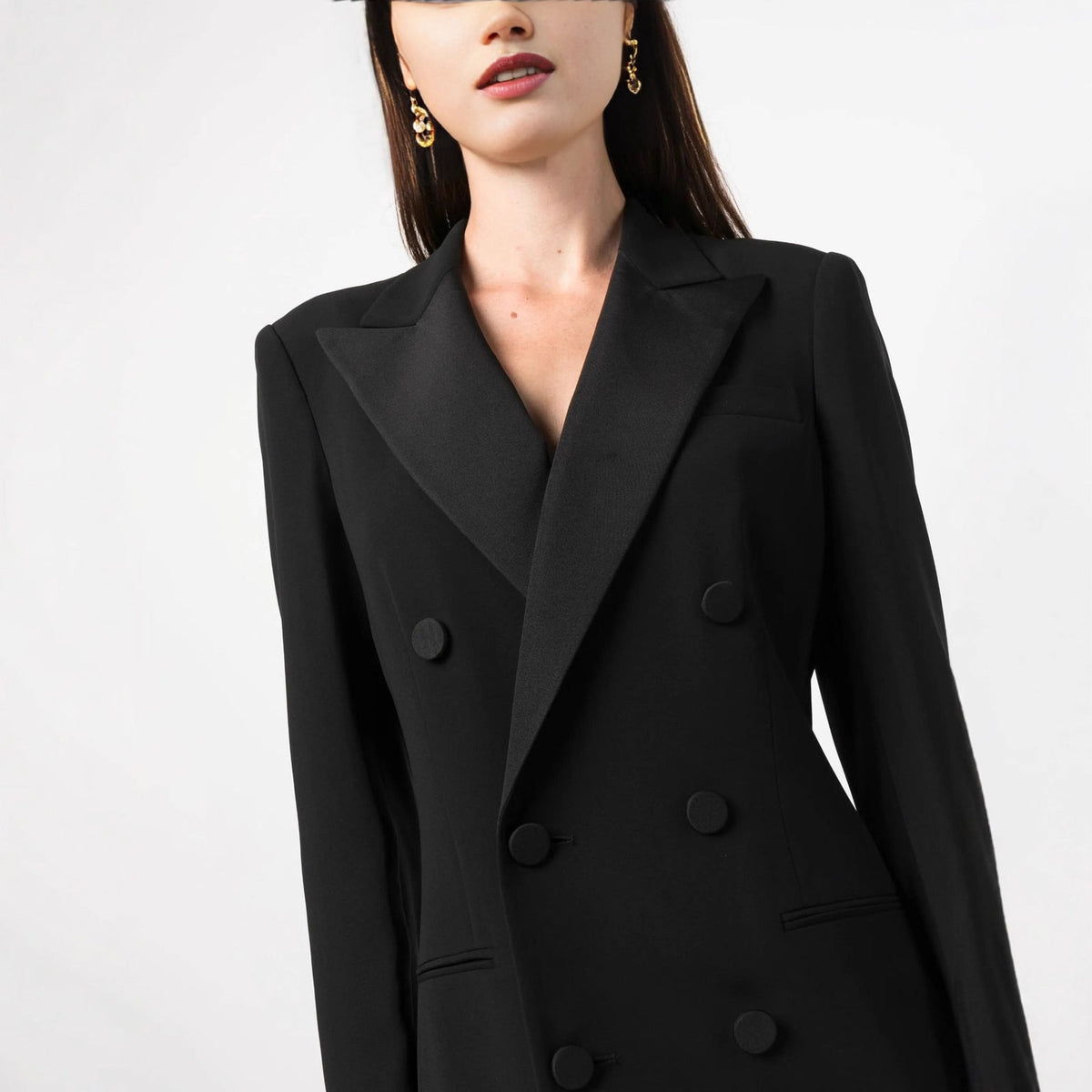 Close-up studio shot of the bodice of a black double-breasted tuxedo maxi dress, showing the satin lapels and buttons.