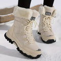 A pair of beige faux fur-lined snow boots with black soles and white laces are shown on a model standing in snow.