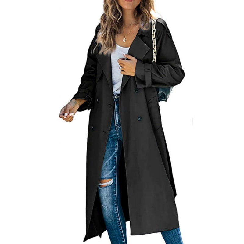 Front view of a woman wearing a black longline double-breasted trench coat over a white top and ripped blue jeans.