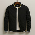 Front view of a black bomber jacket with yellow and white striped ribbed trim, partially unzipped to show a white t-shirt underneath.