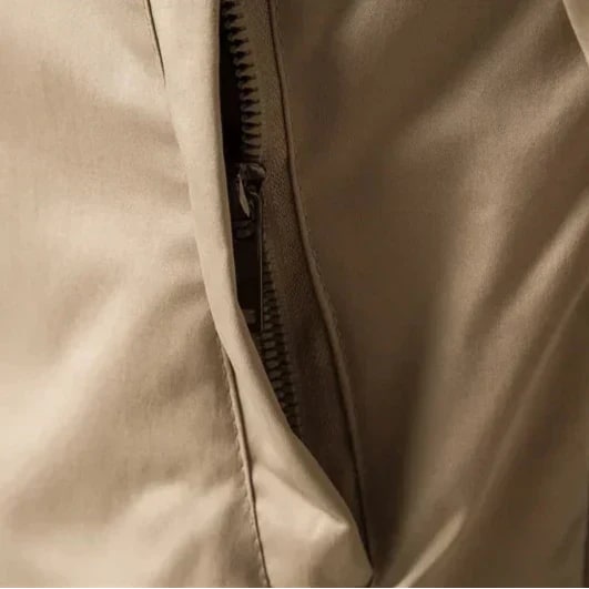 Close-up detail of the beige bomber jacket's zippered side pocket.