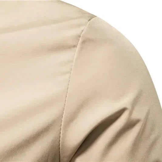 Close-up detail of the shoulder seam and sleeve of the beige bomber jacket.