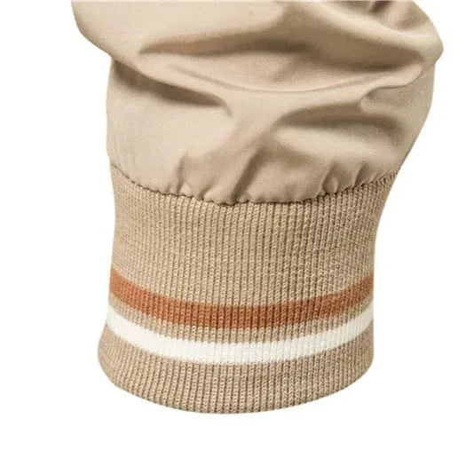 Close-up detail of the striped ribbed cuff of the beige bomber jacket.