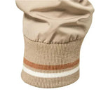 Close-up detail of the striped ribbed cuff of the beige bomber jacket.