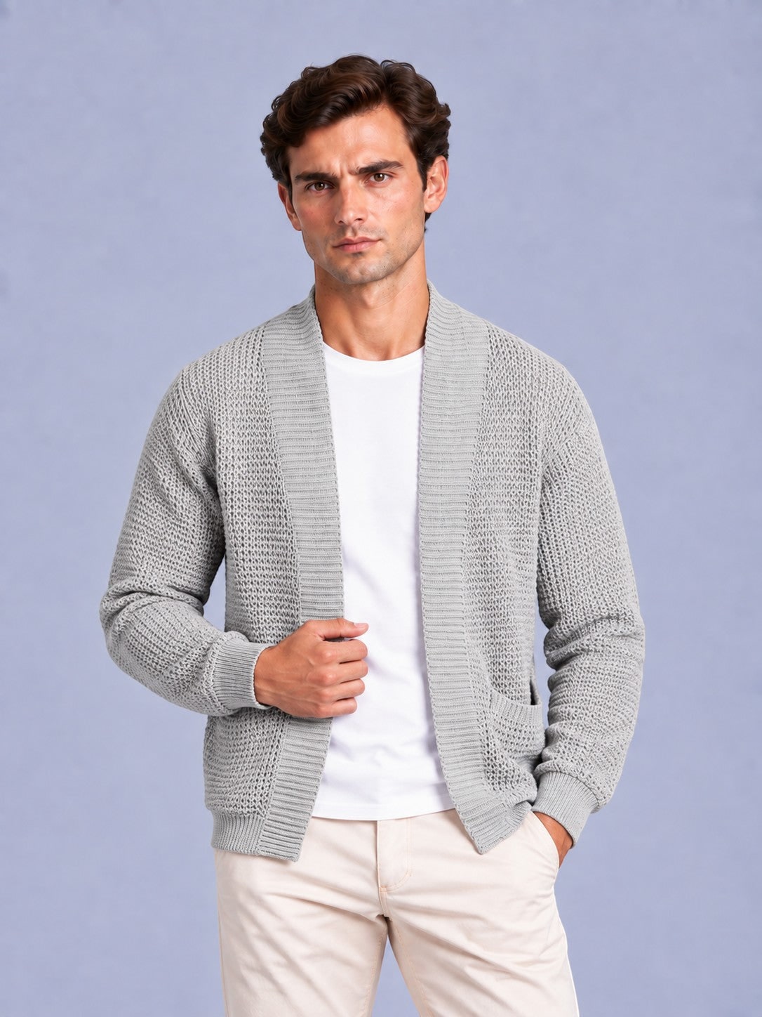 Front view of a man wearing a light grey waffle knit shawl collar cardigan over a white t-shirt and beige trousers.