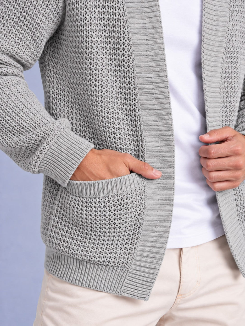 Close-up detail of the light grey waffle knit cardigan, showing the texture, ribbed cuff, and patch pocket with a hand inside.
