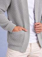 Close-up detail of the light grey waffle knit cardigan, showing the texture, ribbed cuff, and patch pocket with a hand inside.