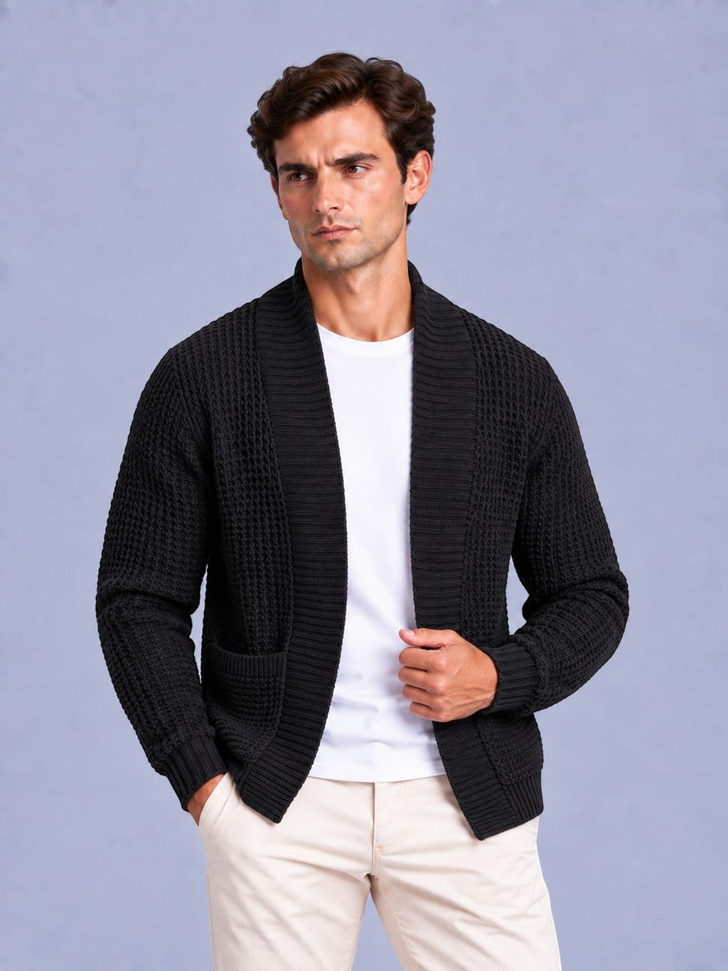 Front view of a man wearing a black waffle knit shawl collar cardigan over a white t-shirt and beige trousers.