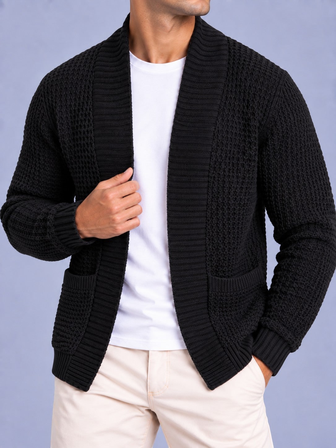 Mid-section front view of a man wearing a black waffle knit shawl collar cardigan, showing the open front and pockets.