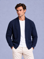 Front view of a man wearing a navy blue waffle knit shawl collar cardigan over a white t-shirt and beige trousers.