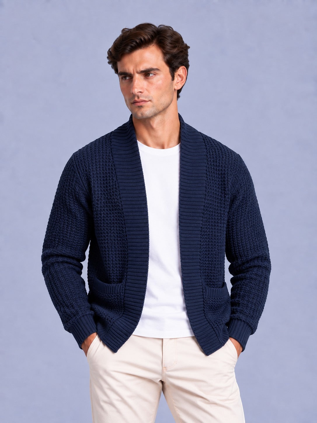 Front view of a man wearing a navy blue waffle knit shawl collar cardigan over a white t-shirt and beige trousers.