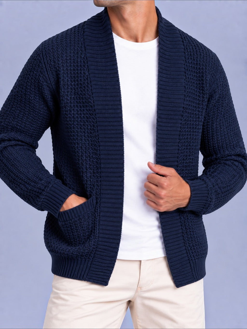 Close-up front view of a man wearing a navy blue waffle knit open cardigan with pockets over a white t-shirt.