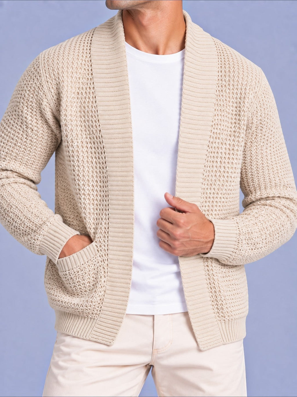 Close-up front view of a man wearing a beige waffle knit open cardigan with pockets over a white t-shirt.
