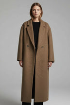 Front view of a woman wearing the brown double-breasted long coat open over a black top and trousers.