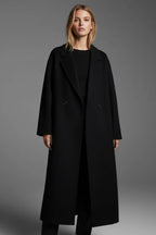 Front view of a woman wearing the black double-breasted long coat open over a black sweater and trousers.