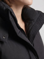 Close-up detail shot of the black puffer jacket's collar, zipper, and snap button closure.