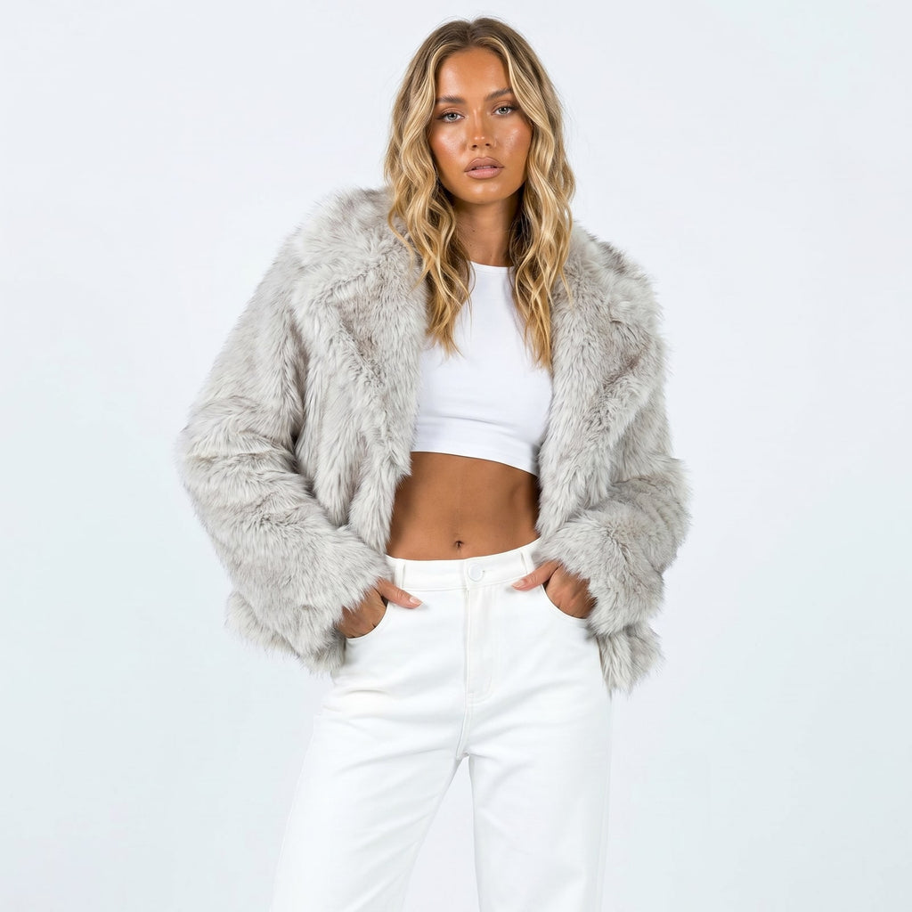 Front view of a woman wearing a light grey faux fur jacket over a white crop top and white pants.