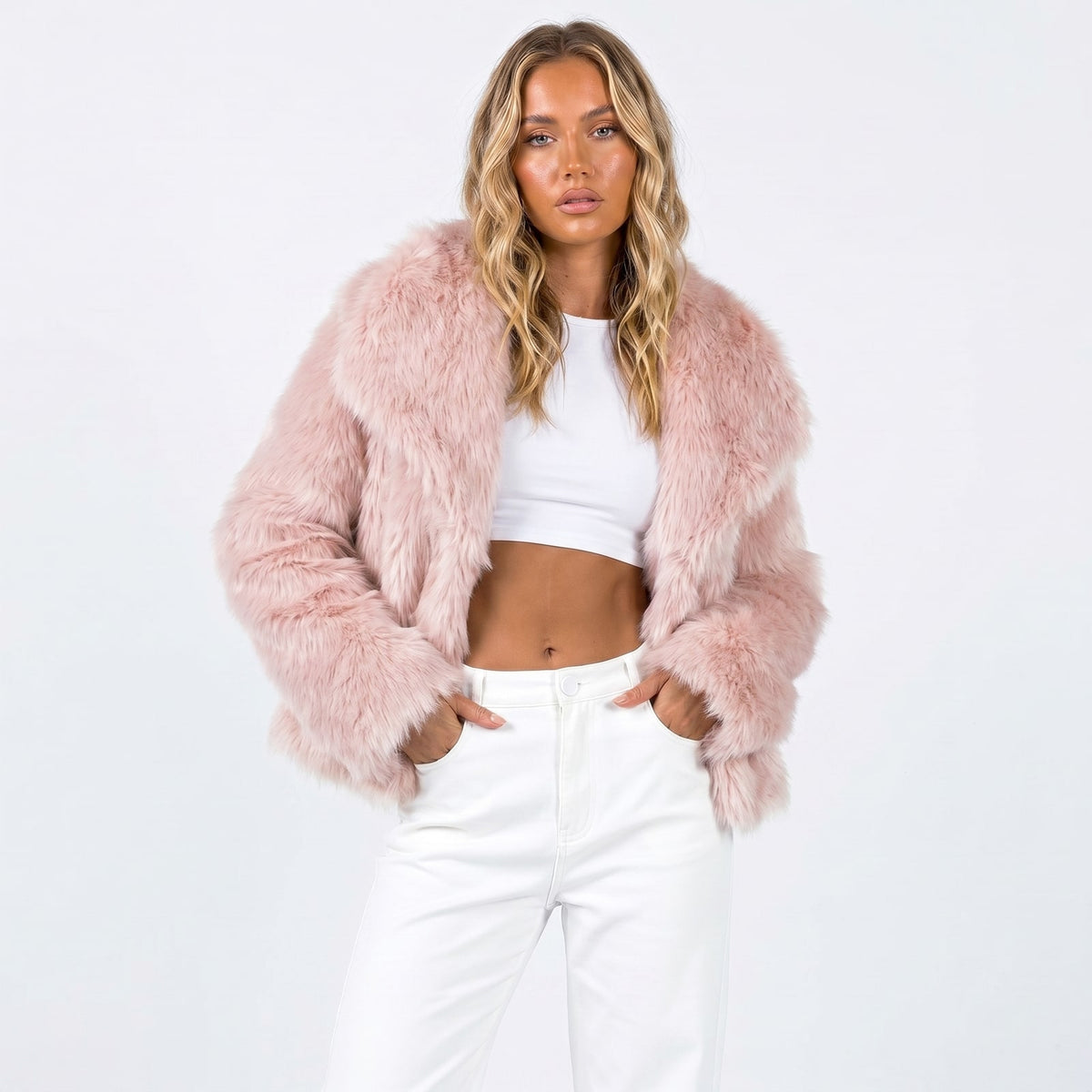 Front view of a woman wearing a pink faux fur jacket over a white crop top and white pants.