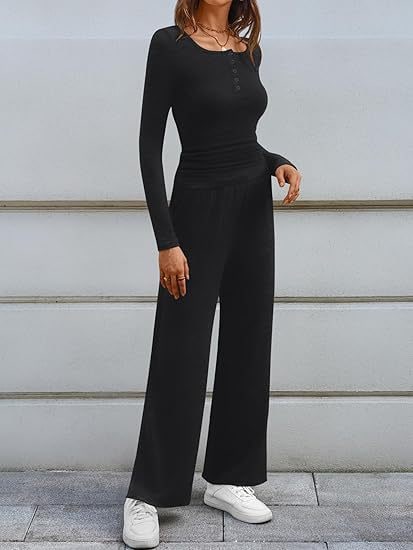 Full body front view of a woman wearing a black ribbed long sleeve henley top and matching wide-leg lounge pants outdoors.