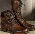 A pair of brown leather lace-up boots, one with the shaft folded down to reveal a fur lining, on a wooden surface.