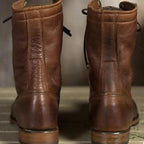 A back view of the pair of brown leather lace-up boots, showing the sturdy construction and heels.