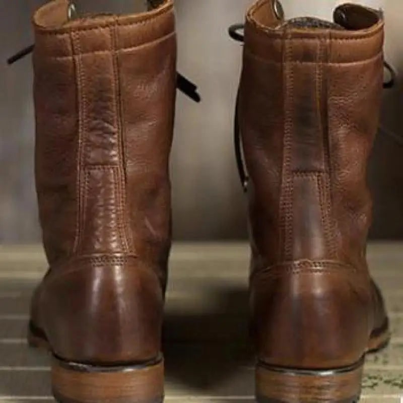 A back view of the pair of brown leather lace-up boots, showing the sturdy construction and heels.