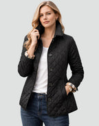 Front view of a woman wearing a black diamond quilted jacket with the collar up and plaid-lined cuffs rolled.