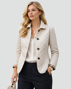 Front view of a woman wearing a cream diamond quilted jacket over a white blouse, with plaid-lined cuffs rolled.