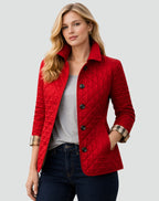 Front view of a woman wearing a red diamond quilted jacket over a grey t-shirt, with plaid-lined cuffs rolled.