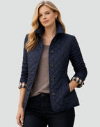 Front view of a woman wearing a navy blue diamond quilted jacket over a brown sweater, with plaid-lined cuffs rolled.