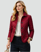Front view of a woman wearing a red diamond quilted jacket over a white blouse, with plaid-lined cuffs rolled.