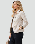 Side view of a woman wearing a cream diamond quilted jacket over a white blouse, with plaid-lined cuffs rolled.